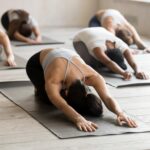 Vier Personen ruhen in der Stellung des Kindes auf Yogamatten in einem hellen Studio.