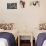 Zimmer mit zwei Einzelbetten, an der Wand zwei Poster mit Pferdemotiv.