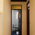 Blick durch einen Flur auf eine Tür mit gelbem Buntglas-Oberlicht.