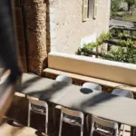 Langer Esstisch mit weißen Stühlen auf einer sonnigen Terrasse.