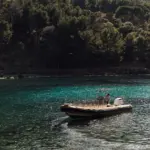 Gelbes Schlauchboot liegt in einer türkisen Bucht vor einem bewaldeten Hang.