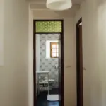 Blick durch einen Flur auf eine Tür mit grünem Buntglas-Oberlicht.
