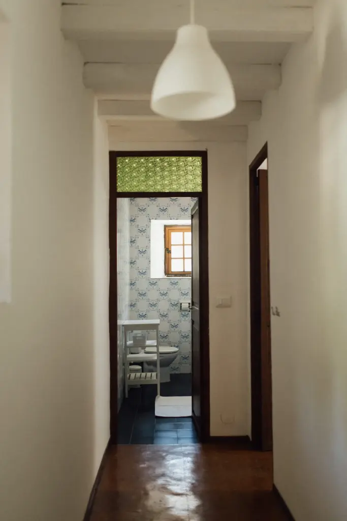 Blick durch einen Flur auf eine Tür mit grünem Buntglas-Oberlicht.