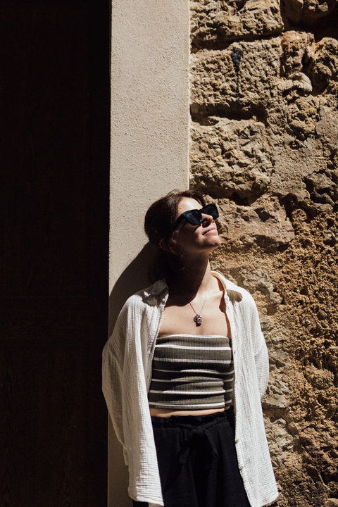 Karin lehnt an einer Steinmauer in der Sonne